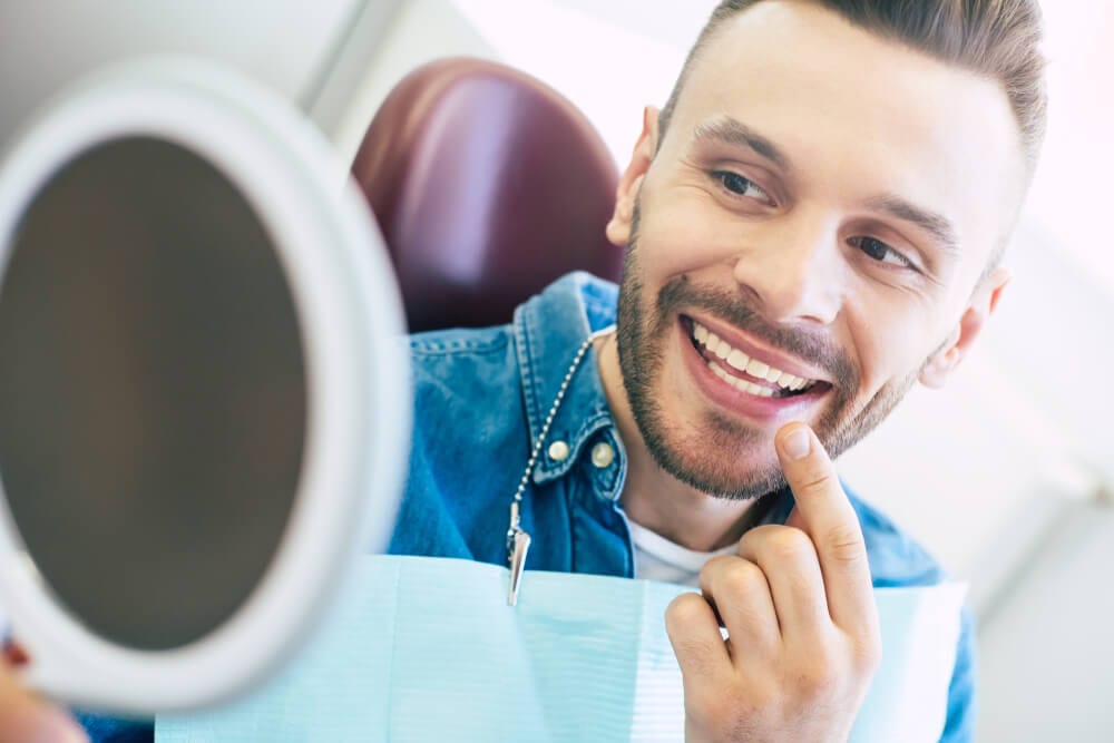 male examining porcelain veneer in the mirror